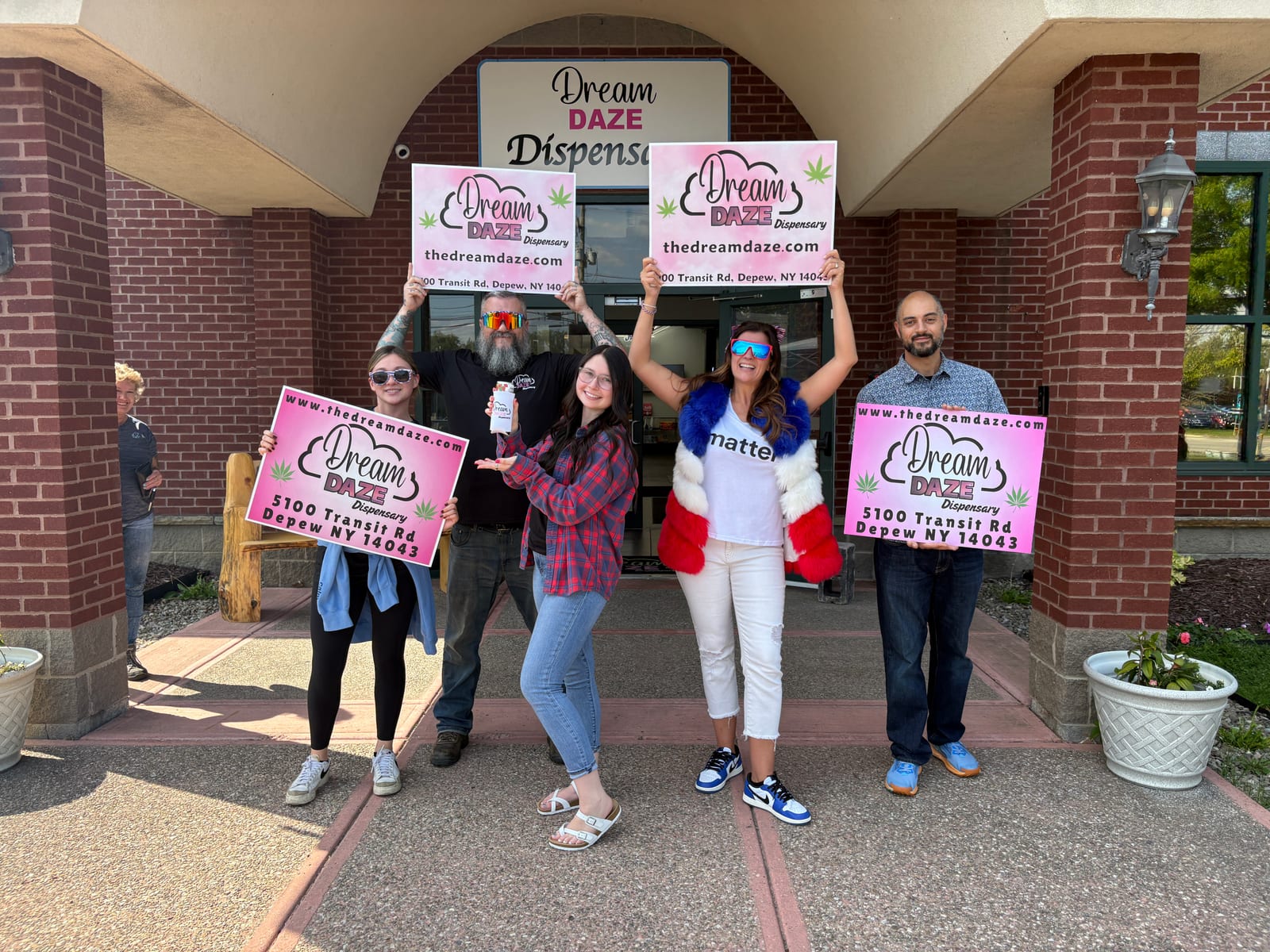 The Dream Daze team holding yard signs outside the Depew shop